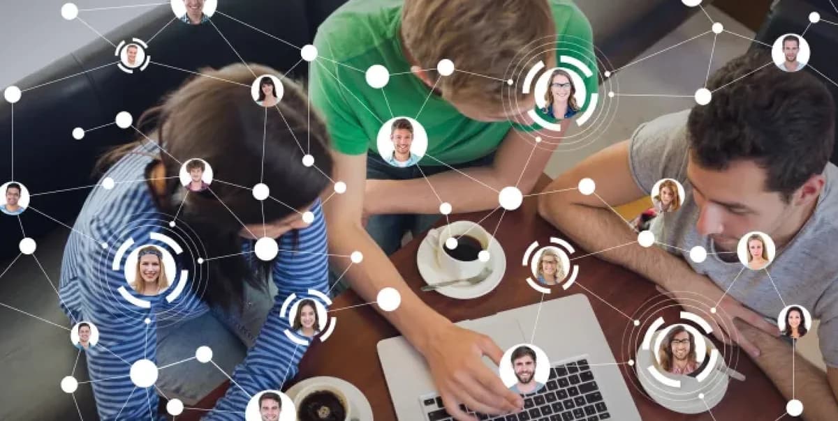 Team collaborating around a wooden table with laptops, overlaid with circular avatar nodes.