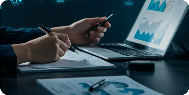 Hands writing notes next to an open laptop displaying governance reference documents and checklists.